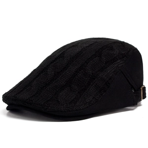 Detail of black cable knit flat cap showing thick texture and side metal buckle