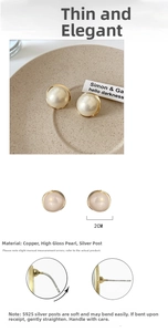Macro detail of high-luster 2cm shell pearl earrings with S925 silver posts on ceramic tray