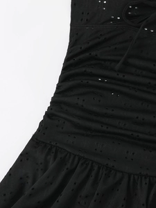 Detailed close-up of black hollow-out fabric featuring pleated texture and ruffle hem