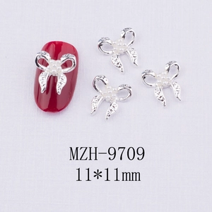 Bijou d'ongle nœud argenté avec perle centrale sur manucure rouge, détail de 11x11mm