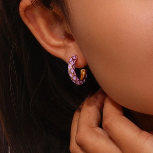 Detailed close-up of purple checkered enamel and gold C-shaped hoop earrings on model