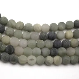 Macro shot of matte natural green grass stone round beads with unique stone textures