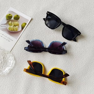 Flat lay of small square frame sunglasses in black, blue texture, and bright yellow colors