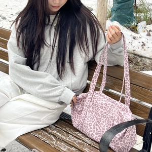 Grande borsa shopper con stampa leopardata rosa su una panca in un paesaggio innevato
