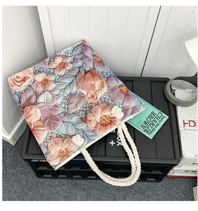 Detail of colorful floral embroidery and thick cotton rope handles on a canvas tote bag