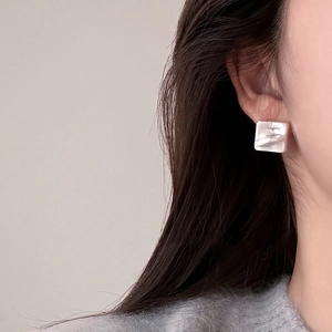Silver geometric square stud earrings with textured finish worn by a model