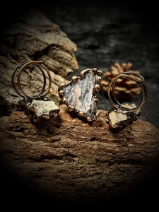 Vue détaillée de bagues artisanales en bronze avec pierres brutes d'agate solaire sur bois