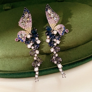 Détail de boucles d'oreilles papillon vintage avec zircons colorés sur velours
