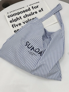Blue and white striped canvas tote bag with Sunday Summer Night print on white desk
