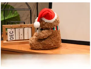 Detail of a brown plush Christmas teddy bear with a striped scarf and festive red hat