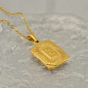Gold stainless steel necklace with rectangular initial B pendant on a textured surface
