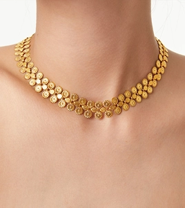 Detail view of a gold plated titanium necklace with intricate floral circular patterns