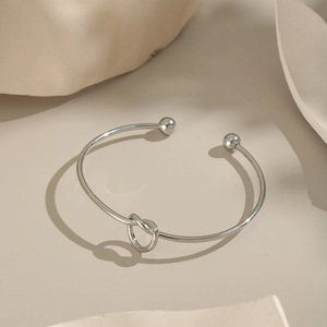 Dettaglio del bracciale a nodo argento minimalista con finitura lucida a specchio