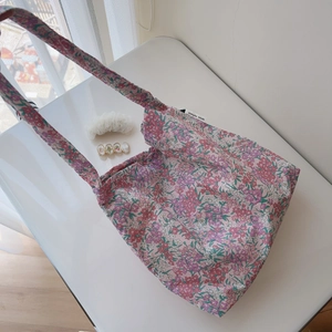 Detail of floral cotton shoulder bag with simple wish label and matching hair accessories