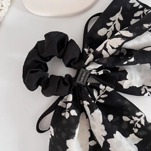 Elegant black scrunchie with floral print ribbon and handmade label on white surface