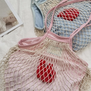 Detailansicht der gewebten Netztaschen in Rosa und Hellblau mit süßen roten Hasenanhängern