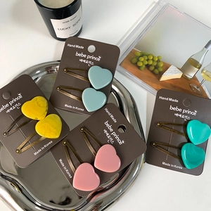 Colorful acetate heart hair clips in blue, yellow, and pink on a stylish metal tray