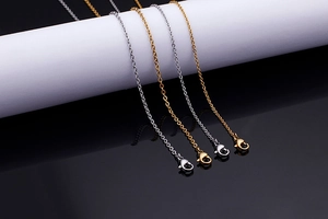 Detailed view of silver and gold link chains with lobster clasps on a cylinder stand