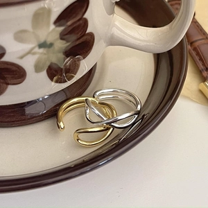 Close-up of minimalist criss-cross silver and gold rings on vintage ceramic decor