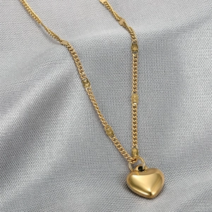 Elegant gold heart pendant necklace for women on silver satin fabric background