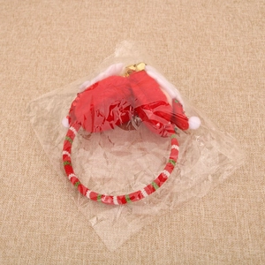 Detail of a Christmas plush headband with red and green stripes, bells, and fluffy pom-poms
