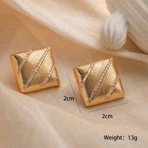 Detailansicht quadratischer goldener Ohrstecker mit diagonalen Strasssteinen auf Satin