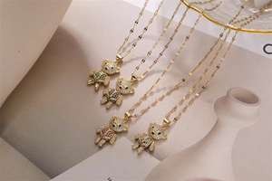 Detailed view of four golden bear necklaces with colorful zircon stones on beige surface