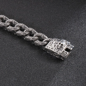 Close-up of gothic stainless steel chain links with skull clasp and floral engravings