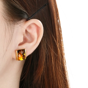 Macro view of square amber glass earrings with 18K gold-plated setting on model
