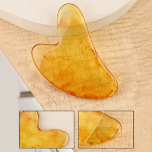 Macro view of heart-shaped amber resin gua sha tool showing smooth texture and clear edges