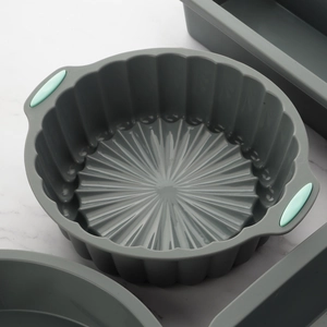 Grey round silicone chiffon cake mold with green handles on a marble surface