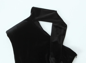 Détail d'une robe en velours noir avec licou et découpe sur fond blanc immaculé