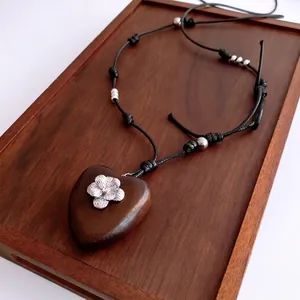 Retro heart wood pendant necklace with metal floral inlay on a black adjustable rope