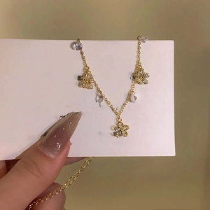 Close-up of a gold flower anklet with sparkling zircon crystals on a white display card