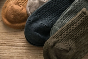 Detaillierte Nahaufnahme von Herren-Zopfstricksocken in Erdtönen auf rustikalem Holz