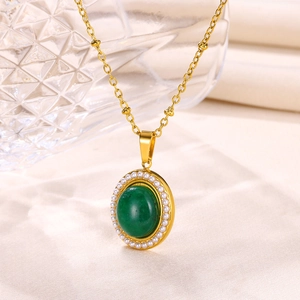 Detail of emerald green oval pendant with white pearl border on a gold chain