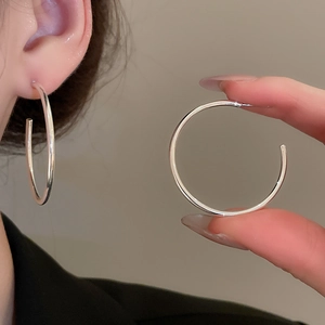 Detail of silver geometric C-shape hoop earrings showing texture and model wearing style
