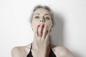 Close-up of a model wearing minimalist silver chain rings and golden twisted hoop earrings
