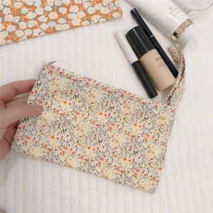 Detail of floral cotton makeup bag with metal zipper and matching wrist strap handle
