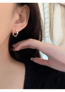 Close-up of a s925 silver wavy hoop earring worn on an ear with polished metal finish