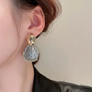 Boucles d'oreilles ovales bicolores or et argent avec texture striée portées par un mannequin