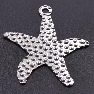 Macro view of starfish pendant with textured silver finish on dark background