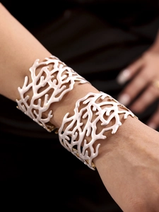 Détail de bracelets manchettes blancs motif corail avec touches dorées sur modèle