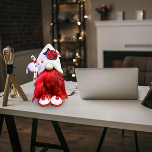 Detail of red Christmas gnome plush with ladybug pattern on a white desk setting