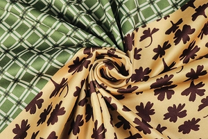 Dettaglio di tessuto patchwork a quadri verdi e trifogli gialli con trama setosa