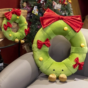 Green plush Christmas wreaths with red velvet bows and cute faces on a cozy sofa