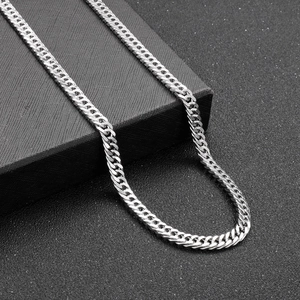 Detailed view of polished stainless steel cuban link chain on black textured background
