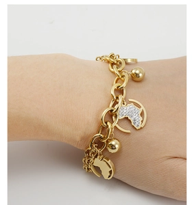 Détail d'un bracelet doré avec des pendentifs carte de l'Afrique et perles au poignet