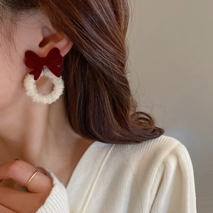 Close-up of red velvet bow earrings with white plush hoop on a model in profile