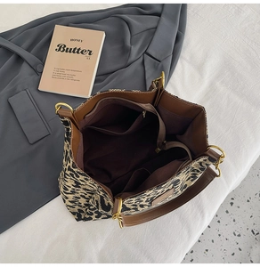 Detail of leopard print tote bag with brown leather trim and organized inner pockets